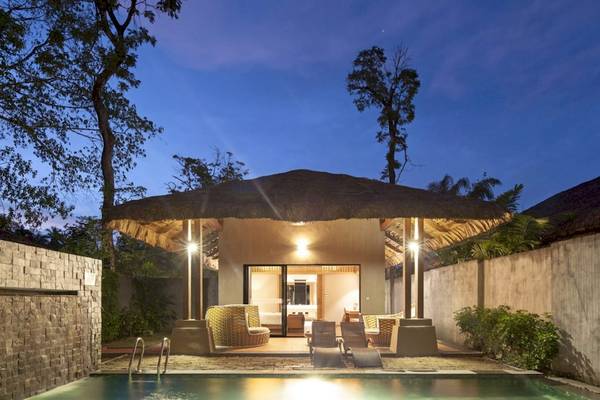 Nachtansicht des Beyond Resorts Khao Lak mit Swimmingpool, Sonnenliegen und beleuchtetem Haus.