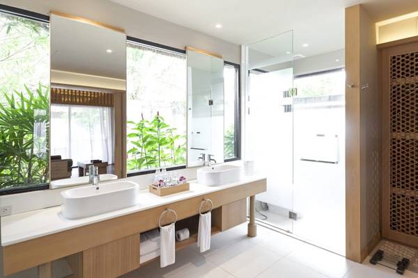 Badezimmer des Beyond Resort Khao Lak mit zwei Waschbecken und einer Dusche.