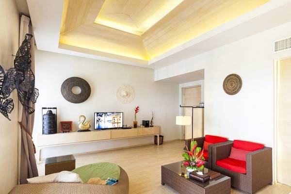 Wohnzimmer im Beyond Resort Khao Lak mit moderner Einrichtung, Holzboden, und einem Fernseher auf einem Tisch.