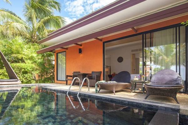 Poolseite des Beyond Resort Khao Lak Villas mit Außenmöbeln und grüner Umgebung.