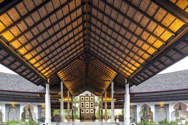 Eingang des Beyond Resort Khao Lak mit traditioneller Dachgestaltung und warmem Licht.