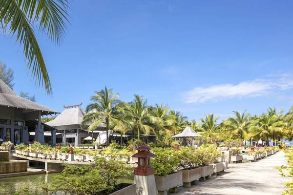Außenansicht des Beyond Resort Khao Lak mit Gebäuden, Palmen und Wassergarten.
