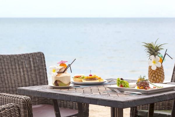 Esstisch am Strand des Beyond Resorts Khao Lak mit Cocktails, Desserts und Meeresblick.