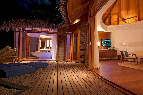 Außenbereich des Constance Halaveli Maldives Hotels bei Nacht mit offenem Eingang und gepolsterten Sitzplätzen.