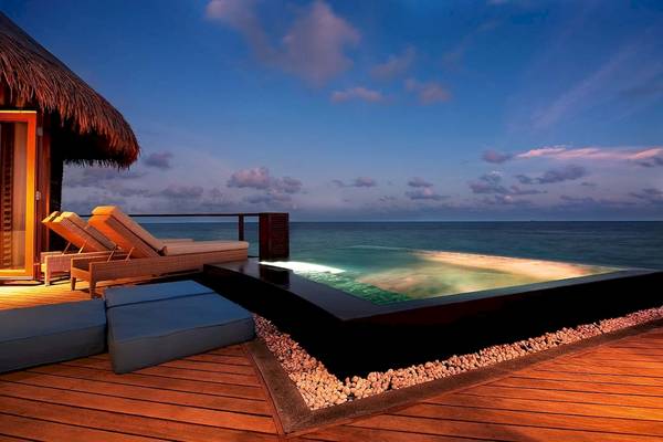 Abendszene am Infinity-Pool des Constance Halaveli Maldives Hotels mit Blick auf den Ozean.