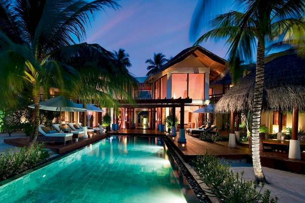 Nachtansicht des Constance Halaveli Maldives Hotels mit Swimmingpool und Loungestühlen.