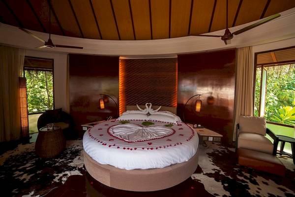 Schlafzimmer im Constance Halaveli Maldives Hotel mit Herzbett und Ausblick auf den Dschungel.