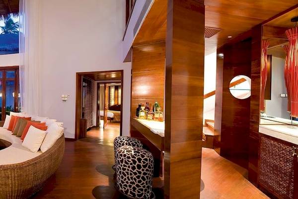 Wohnbereich des Constance Halaveli Maldives Hotels mit Sofa, Tisch und Fernseher.