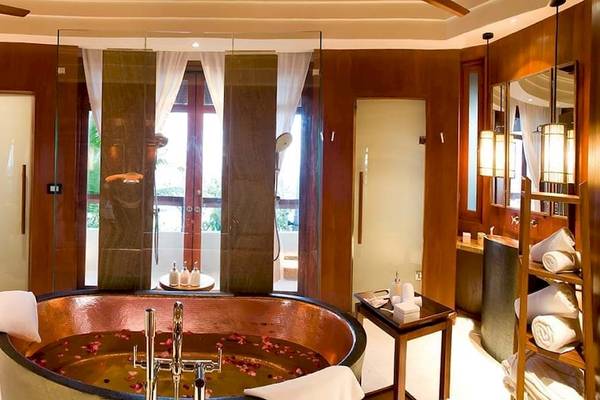Badezimmer im Constance Halaveli Maldives mit großer Badewanne, Holzwänden und Glastür.