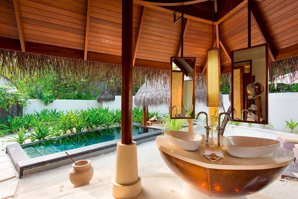 Außenbadezimmer im Constance Halaveli Maldives mit Swimmingpool und grüner Umgebung.