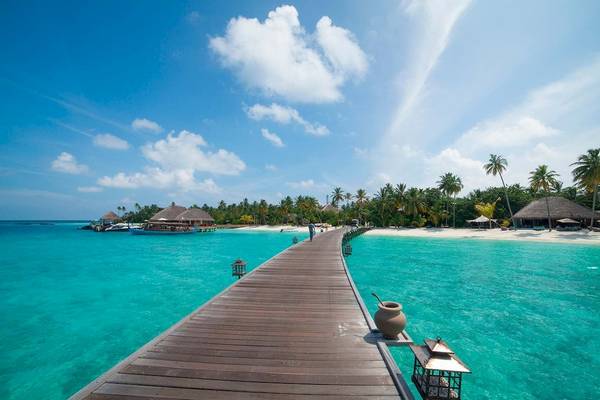 Promenade am Constance Halaveli Maldives Strand mit blauem Wasser und Palmen