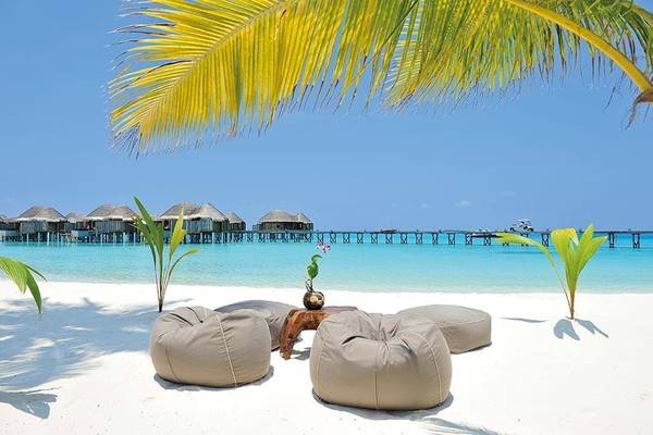 Strand des Constance Halaveli Maldives Hotels mit Palmen und Wasserliegen