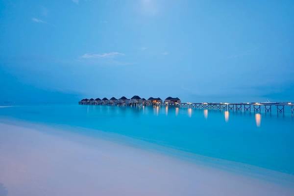 Abendstimmung im Constance Halaveli Maldives mit Wasservillen und hellem Himmel.