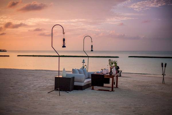 Abendstimmung am Strand des Constance Halaveli Maldives mit Loungemöbeln und Laternen.