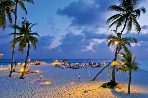 Abendveranstaltung am Strand des Constance Halaveli Maldives Hotels mit illuminierten Tischen und Palmen.