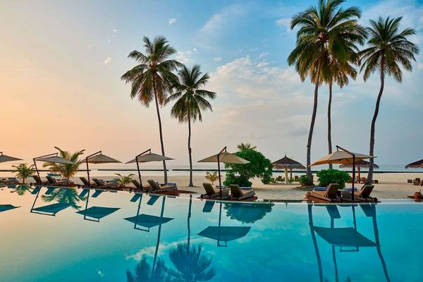 Außenpool des Constance Halaveli Maldives bei Sonnenuntergang mit Sonnenliegen und Palmen