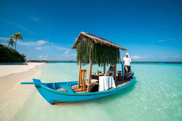 Blaues Boot mit einem Tisch auf dem Wasser im Constance Halaveli Maldives