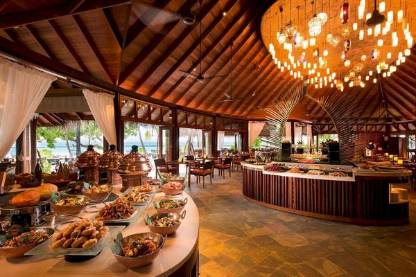 Innenansicht des Restaurants im Constance Halaveli Maldives mit vielen Speisen und Dekoration.