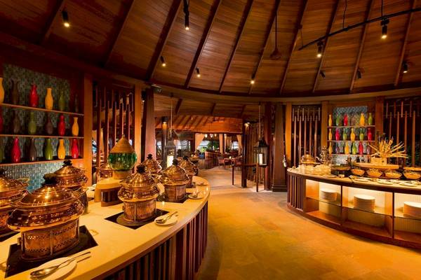 Innenansicht des Restaurants im Constance Halaveli Maldives Hotel mit Speisen auf einer Theke und Vasen an der Wand.