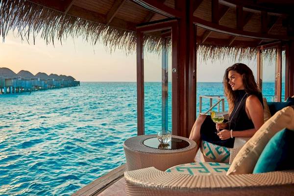 Frau auf dem Sofa im Constance Halaveli Maldives mit Blick auf das Meer