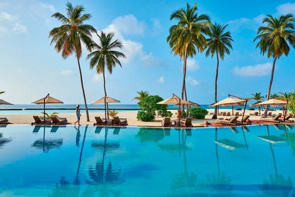 Constance Halaveli Maldives Pool mit Loungestühlen und Sonnenschirmen am Strand