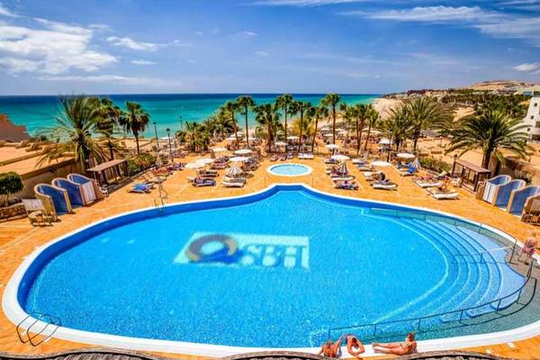 Luftaufnahme des SBH Taro Beach Pools mit vielen Sonnenliegen und Palmen am Strand