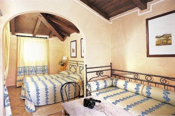 Doppelzimmer im Colonna Country & Sporting Club mit zwei Betten, Tisch, Kamera und Gemälden an der Wand.