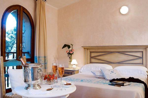 Hotelzimmer im Colonna Country & Sporting Club mit Champagner und Früchten auf einem Tisch.