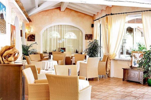 Innenansicht des Restaurants im Colonna Country & Sporting Club mit runden Tischen und Stühlen.