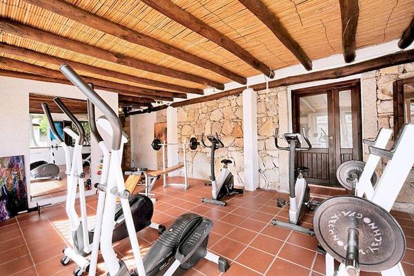 Fitnessraum im Colonna Country & Sporting Club mit Holzbalkendecke und Steinwand.