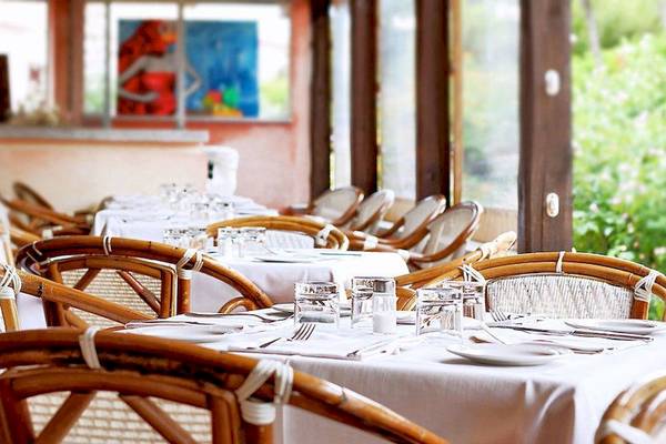 Innenansicht des Restaurants im Colonna Country & Sporting Club mit gedeckten Tischen und Stühlen.