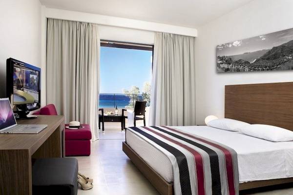 Ein Hotelzimmer im Atlantica Eleon Grand Resort mit einem Bett, Schreibtisch und einem Ausblick auf das Meer.