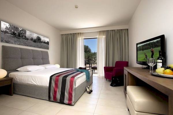 Foto eines eleganten Hotelzimmers im Atlantica Eleon Grand Resort, mit einem Doppelbett, Fernseher und Möbeln.