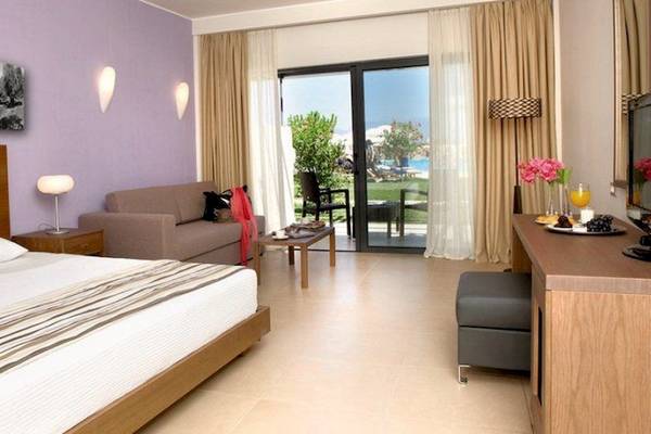 Hotelzimmer im Atlantica Eleon Grand Resort mit Bett, Couch, Tisch und Terrassentür.