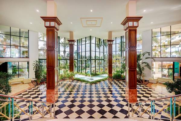 Lobby des Hipotels Natura Palace mit schwarzen und weißen Fliesen und großen Glaswänden.