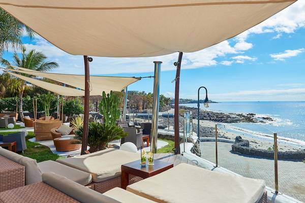Terrasse des Hipotels Natura Palace mit Blick auf das Meer und Loungemöbeln.