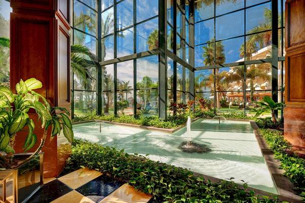 Innenpool des Hipotels Natura Palace mit Glaswänden und Pflanzen.