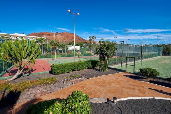 Tennisplatz im Hipotels Natura Palace Hotel mit grünem Rasen und roten Sand.