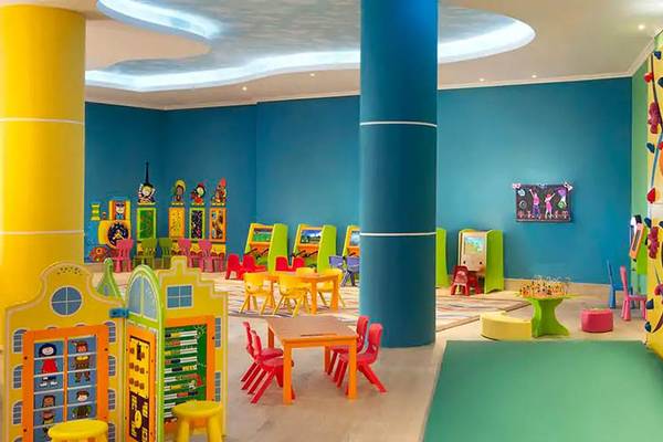 Das kinderfreundliche Spielzimmer im DoubleTree by Hilton Resort & Spa Marjan Island mit bunten Möbeln und einer Kletterwand.