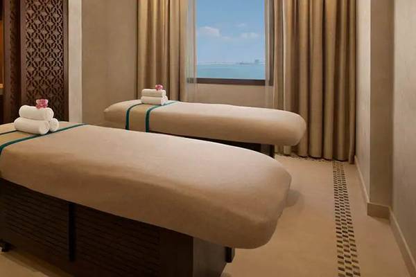 Behandlungsraum im DoubleTree by Hilton Resort & Spa Marjan Island mit zwei Massagetischen und Blick auf das Meer.