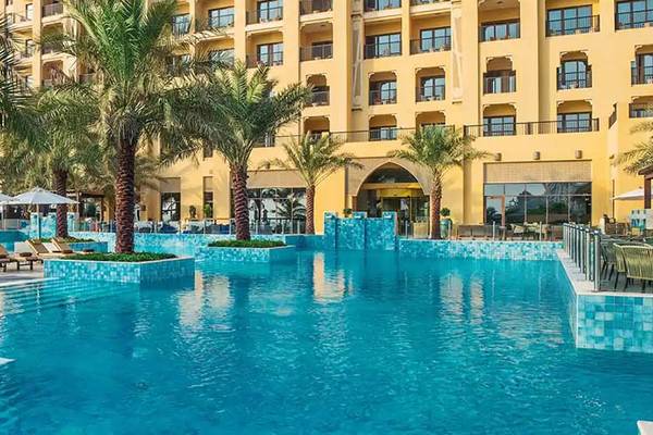 Außenpool des DoubleTree by Hilton Resort & Spa Marjan Island mit Loungestühlen und Palmen