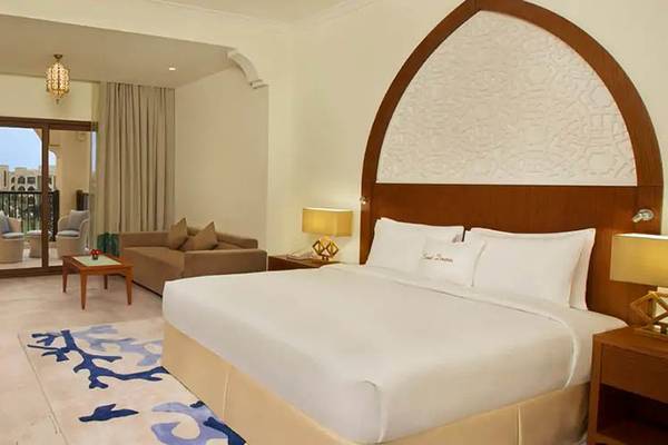 Doppelzimmer im DoubleTree by Hilton Resort & Spa Marjan Island mit Bett, Fernseher und Wohnzimmer.