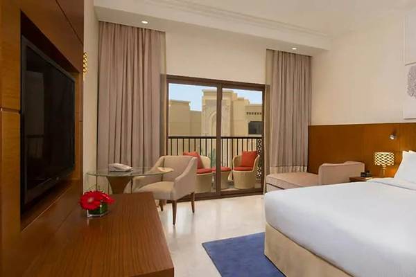 Hotelzimmer im DoubleTree by Hilton Resort & Spa Marjan Island mit Bett, Fernseher, Tisch und Balkonzugang.