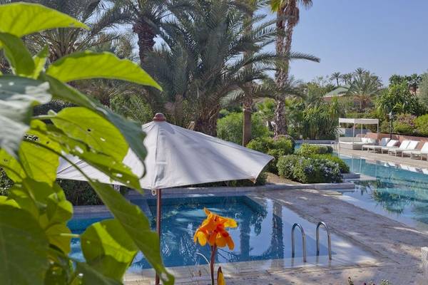 Palmeraie Palace Poolbereich mit Schirm und Sonnenliegen.