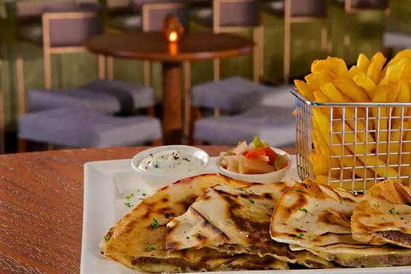 Ein Teller mit gegrillten Quesadillas, Beilagen und Pommes frites in einem Restaurant.