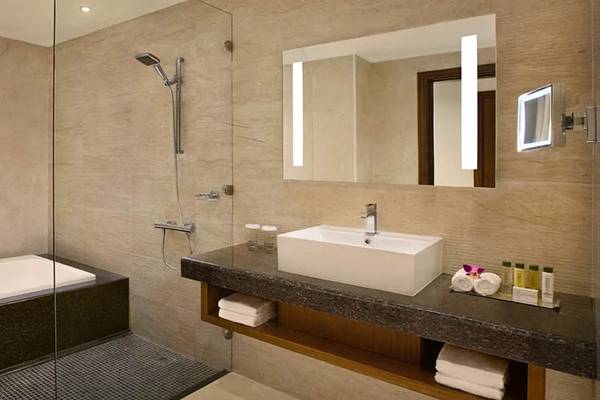 Badezimmer im DoubleTree by Hilton Resort & Spa Marjan Island mit Badewanne, Glasdusche, Spiegel und Waschbecken.