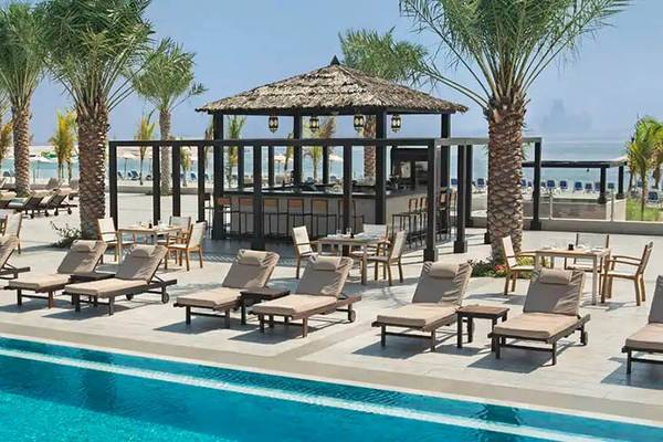 Poolbereich des DoubleTree by Hilton Resort & Spa Marjan Island mit Loungeliegen und einem kleinen Pavillon.