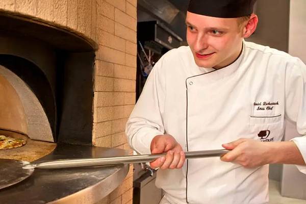 Koch im DoubleTree by Hilton Resort & Spa Marjan Island, der Pizza im Ofen zubereitet.
