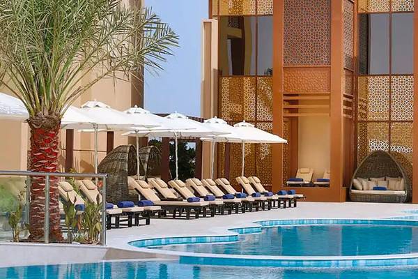 Außenbereich des DoubleTree by Hilton Resort & Spa Marjan Island mit Swimmingpool und Sonnenliegen.