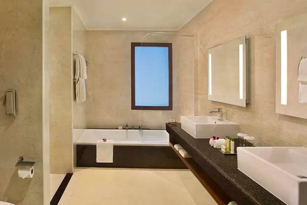 Badezimmer im DoubleTree by Hilton Resort & Spa Marjan Island mit Badewanne und zwei Waschbecken.